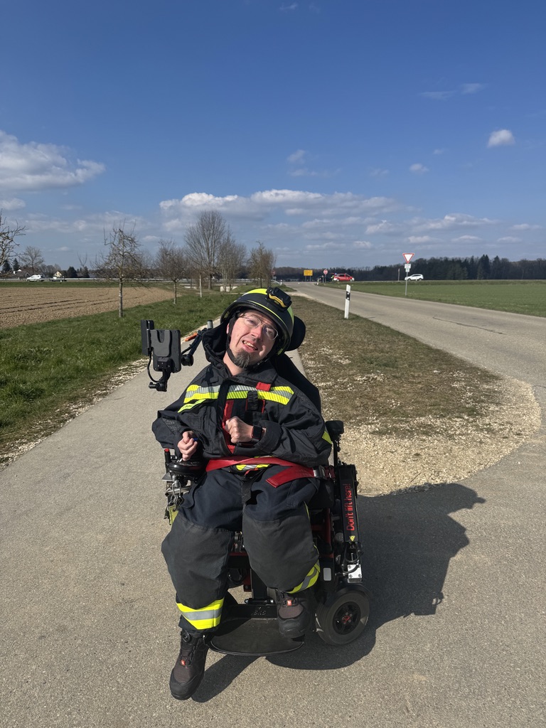 Thomas Burghart im Feuerwehrschutzanzug in seinem Elektrorollstuhl